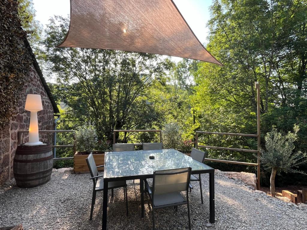 a glass table and chairs on a patio at Petit maison du Vallon in Marcillac-Vallon