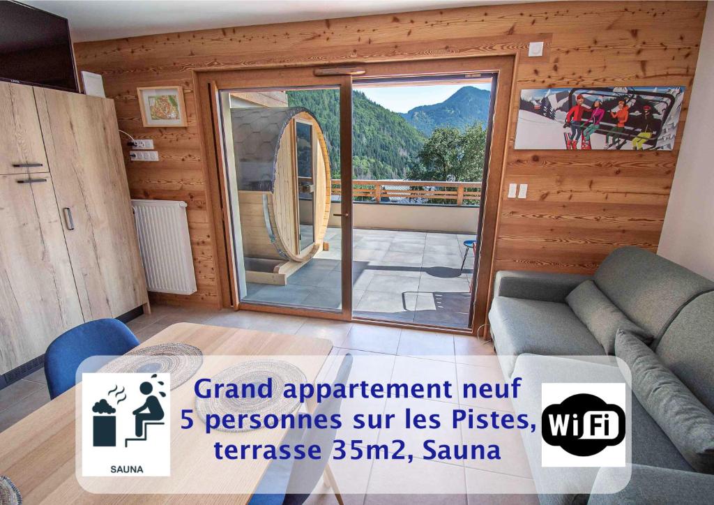 a living room with a couch and a large glass door at Dans résidence neuve LE SNOW ROC sur les pistes, grand studio cosy 5 pers avec terrasse panoramique, SAUNA, WIFI in Saint-Jean-dʼAulps