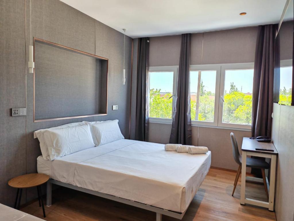 a bedroom with a large white bed with windows at Hotel Golden Alcorcon in Alcorcón