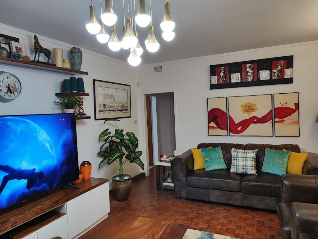 Una sala de estar con un sofá y un televisor de pantalla plana. en Hodson Villa, en Harare