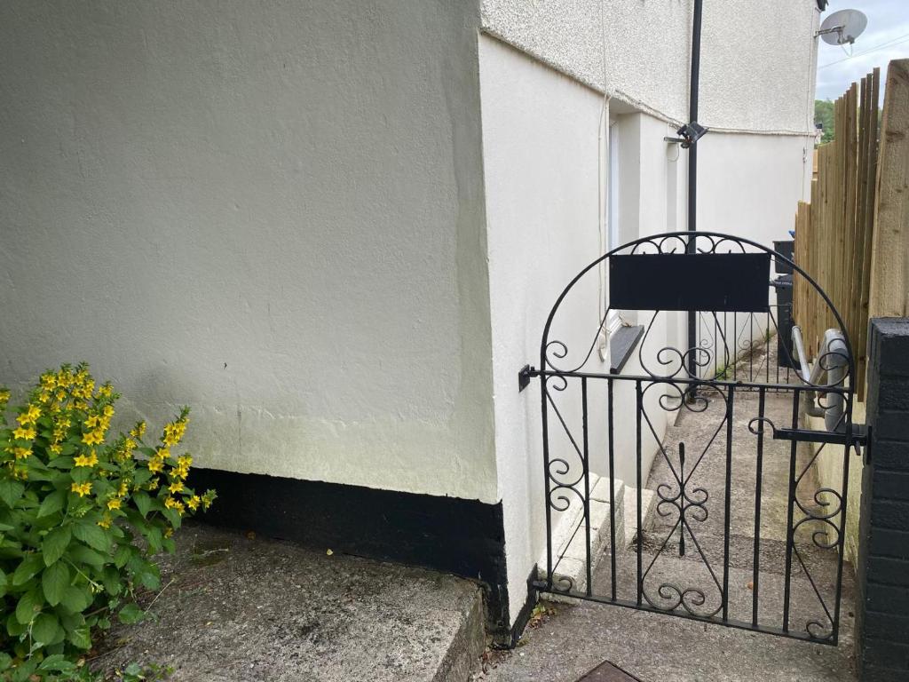 a gate on the side of a building with flowers at Brithdir Cottage in Merthyr Tydfil