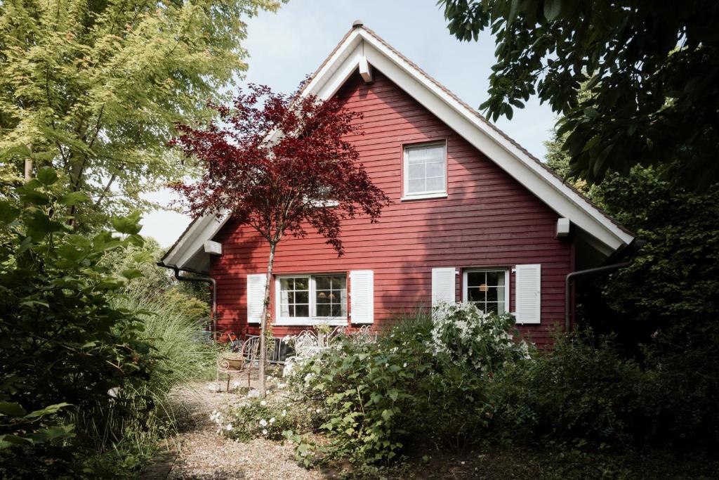 een rood huis met een boom ervoor bij EDEN COTTAGE, Bezauberndes Schwedenhaus mit Garten und Kamin in Stein am Rhein