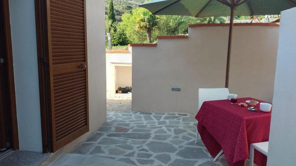 a patio with a table and an umbrella at Villa il Poderino in Marina di Campo
