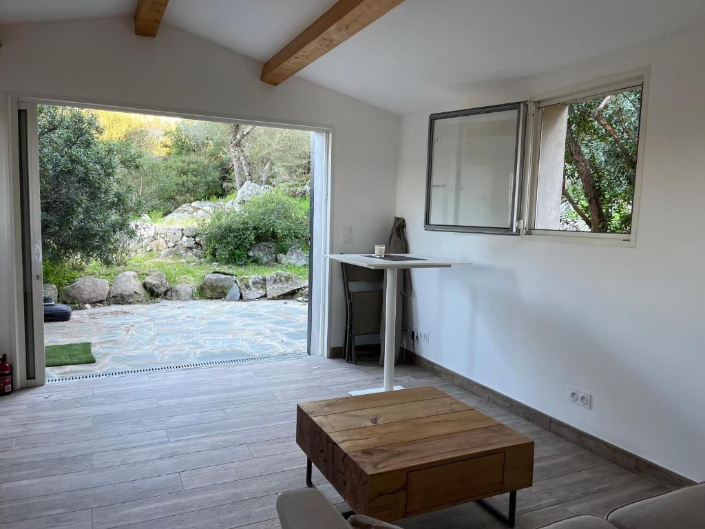 un salon avec une table et une grande fenêtre dans l'établissement La campagne au bord de la mer, à Porto-Vecchio