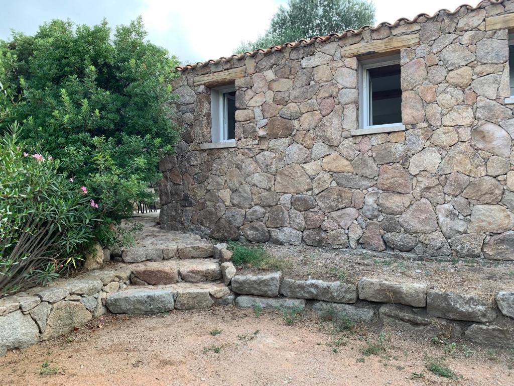 un edificio de piedra con una pared de piedra y 2 ventanas en La campagne au bord de la mer, en Porto Vecchio