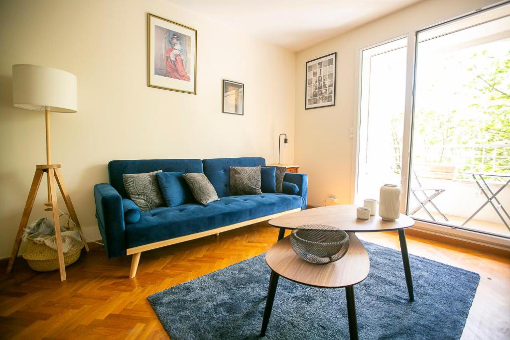 un salon avec un canapé bleu et une table dans l'établissement Jerickais appartement à la Défense, à Courbevoie