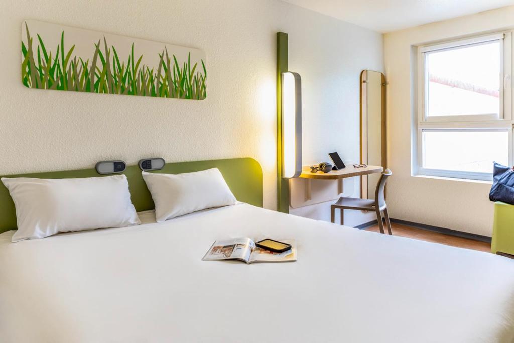 a bedroom with a white bed with a book on it at ibis budget Compiègne Centre-Ville in Compiègne