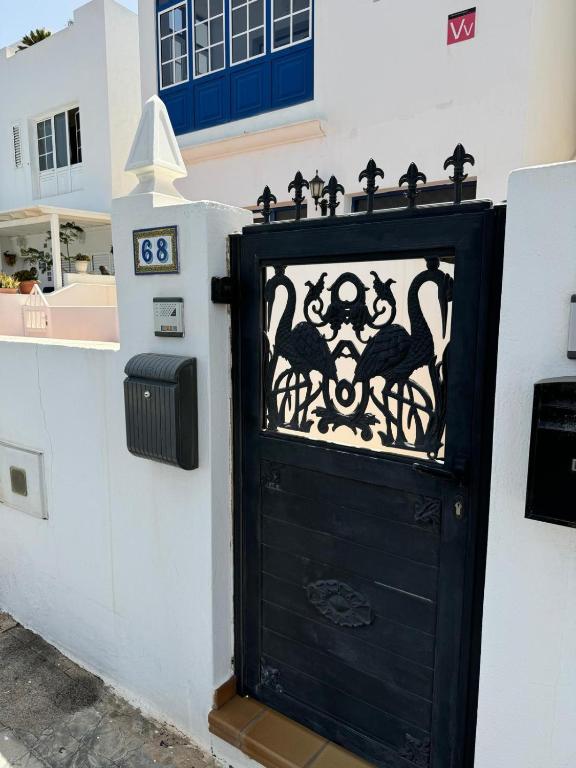 a black door with birds on a white wall at Casa Cueva de los Verdes in Punta Mujeres