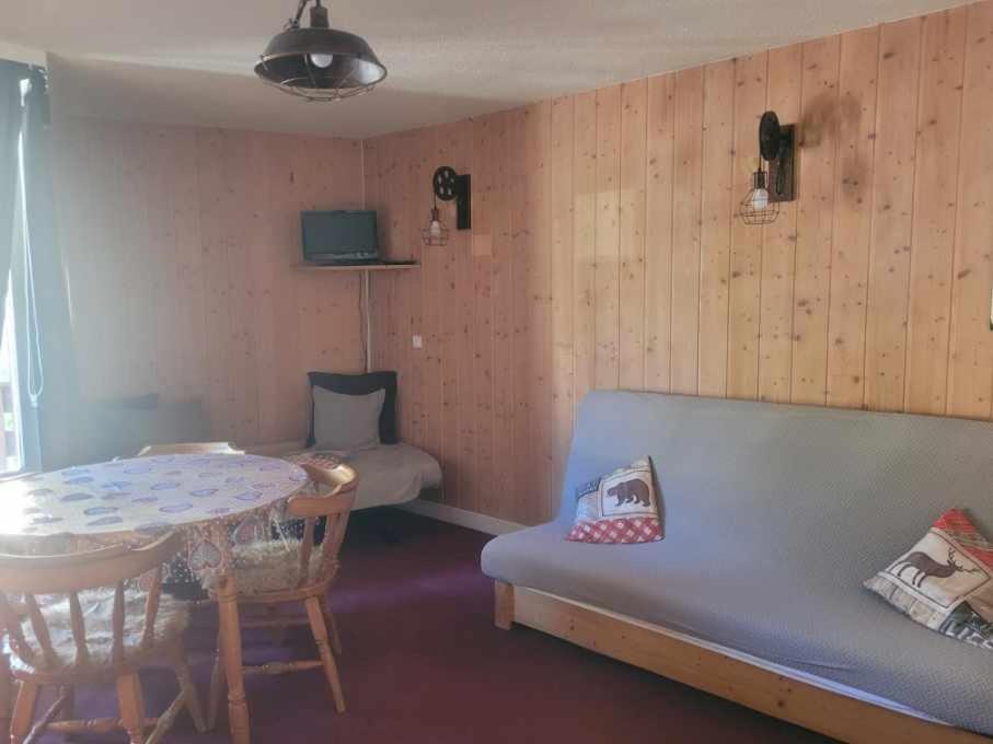une pièce avec un canapé bleu et une table et une table dans l'établissement Jolie studio pied des pistes, à Orcières