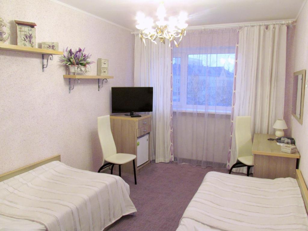 Schlafzimmer mit einem Bett, einem Schreibtisch und einem TV in der Unterkunft Hotel Vetraz in Wizebsk