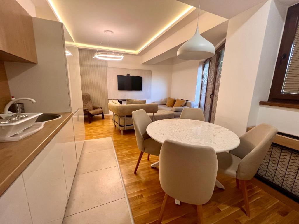 a kitchen and a living room with a table and chairs at Gigi Apartment by eluxory in Skopje