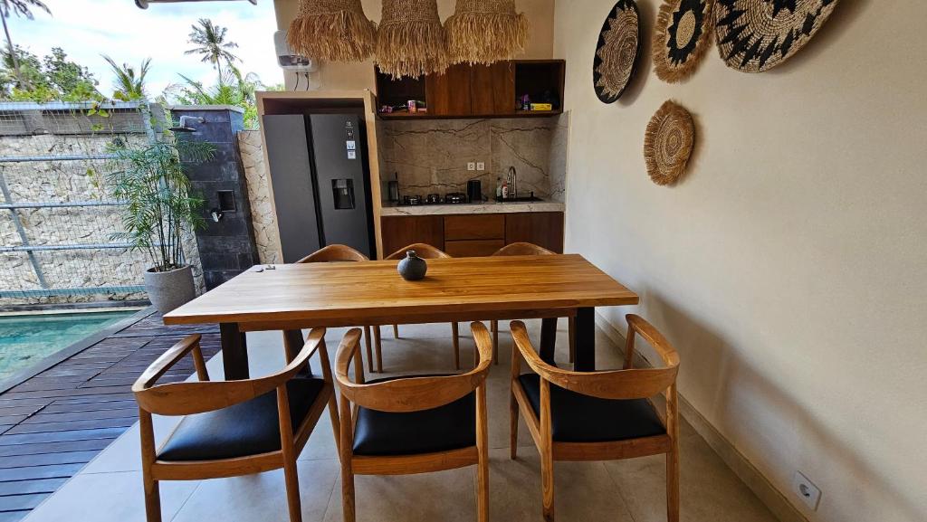 a kitchen with a wooden table and chairs at LM Home Mendira in Candidasa