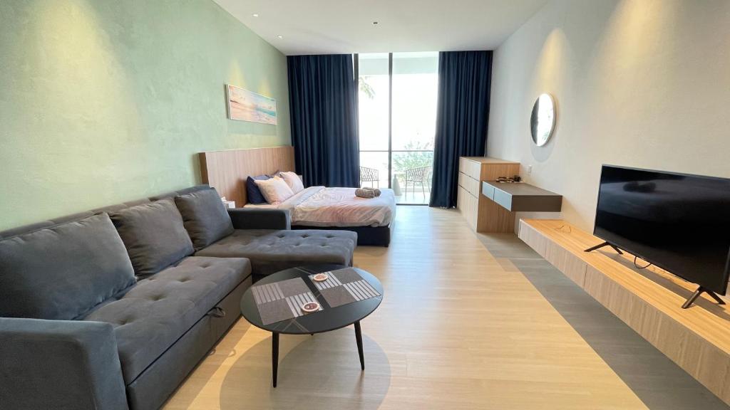 een woonkamer met een bank en een tv bij Freedom Flamingos-RoxyBeachApt in Sematan