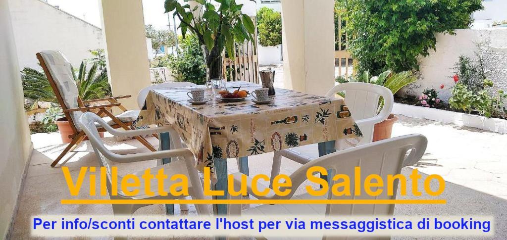 Una mesa con sillas blancas alrededor en un patio. en Villetta Luce Salento, en Marina di Pescoluse