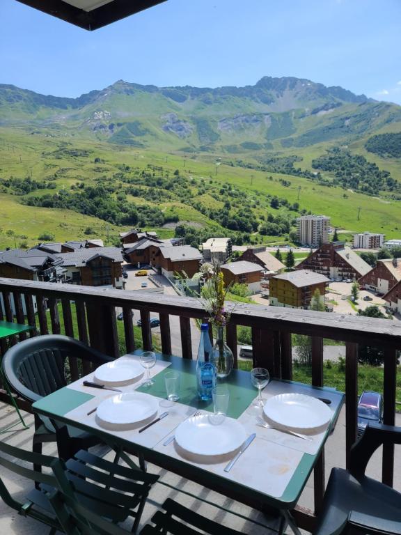 une table avec des assiettes et des verres à vin sur un balcon dans l'établissement Edelweiss17, à Saint-François-Longchamp