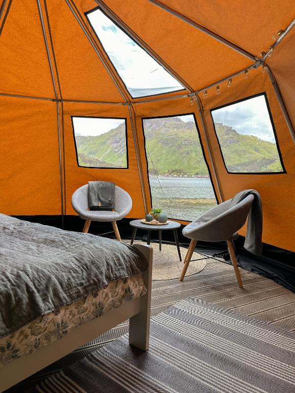 a room with a bed and two chairs and windows at FLO Lofoten nature escape in Valberg