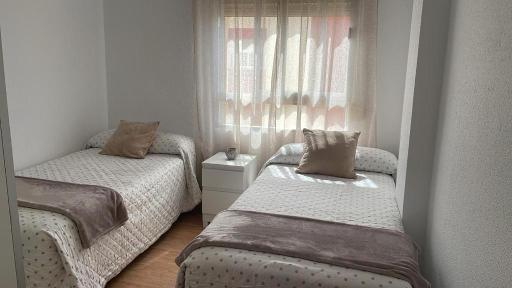 a small bedroom with two beds and a window at Piso acogedor en Barbate in Barbate
