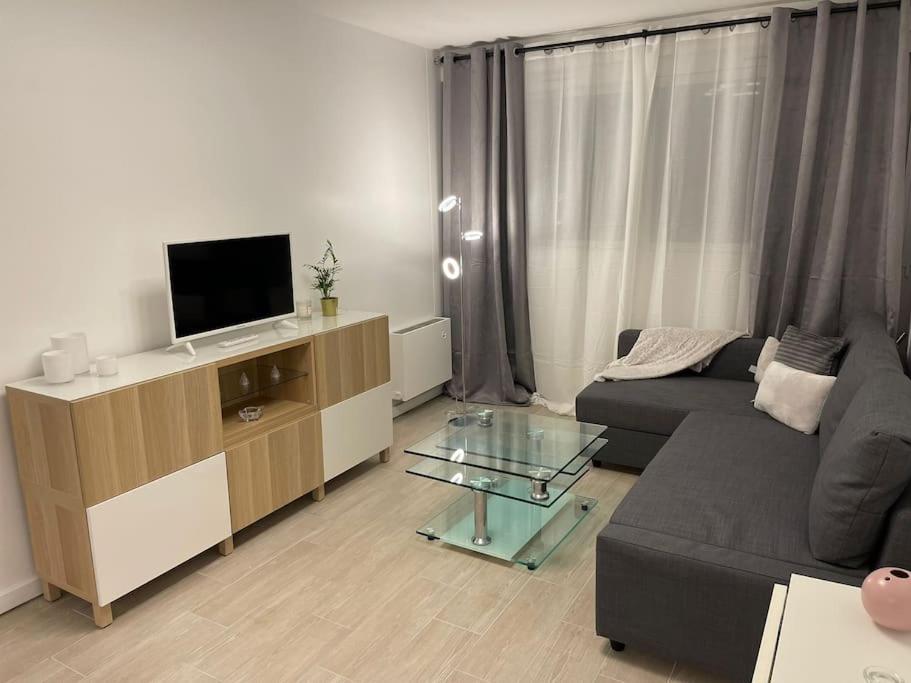 un salon avec un canapé et une télévision dans l'établissement T1 standing LA DÉFENSE - 10 min PARIS & U ARENA, à Courbevoie