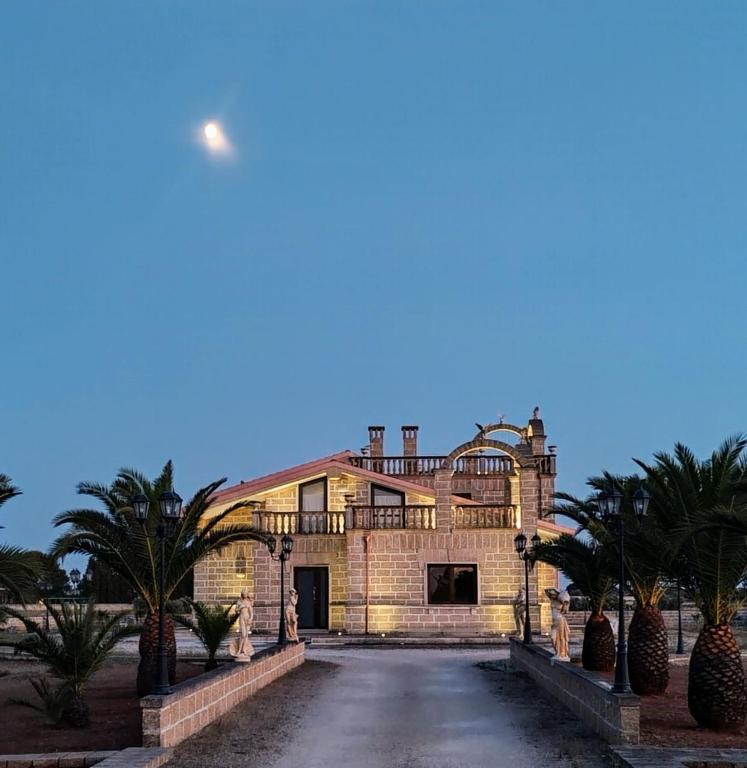 a large house with palm trees in front of it at Castlehawk Resort in Galatone
