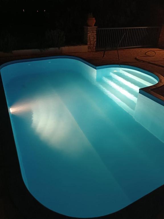 a blue swimming pool lit up at night at Skradin villa et studio in Dubravice