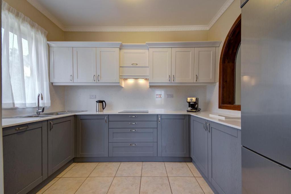 a kitchen with white cabinets and a sink at Baldacchino Holiday Villas in Mellieħa