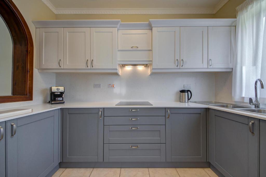 a kitchen with white cabinets and a sink at Baldacchino Holiday Villas in Mellieħa