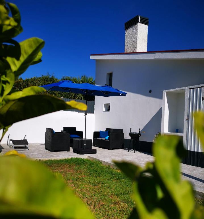 a patio with chairs and a blue umbrella at Casa la Grenadine in Esmoriz