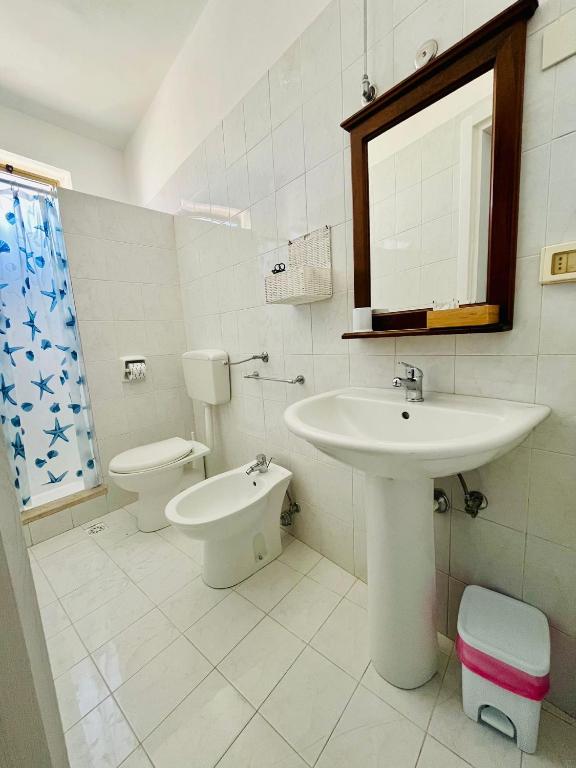 a white bathroom with a sink and a toilet at Hotel Giglio in Lampedusa