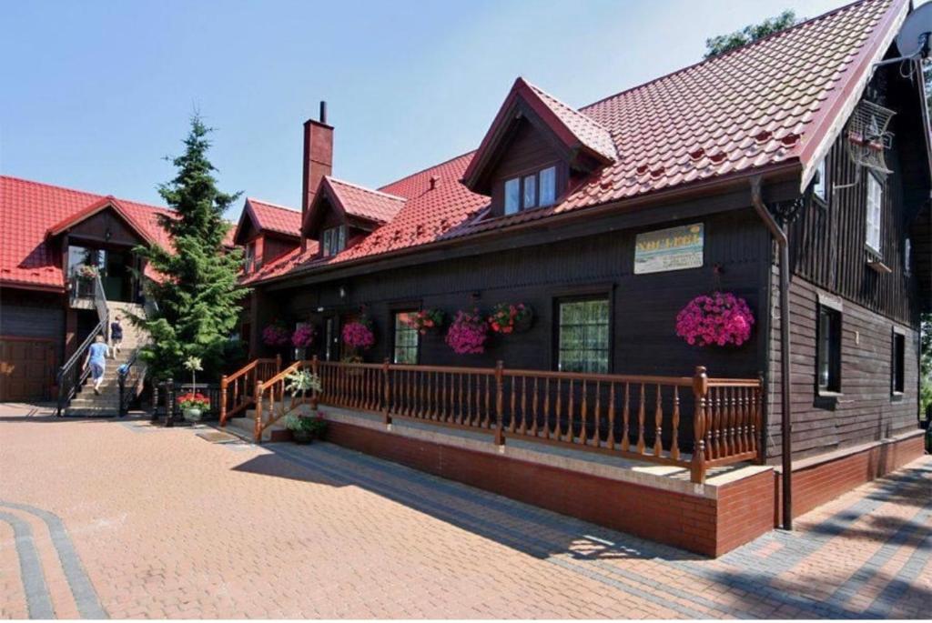 a wooden building with a red roof at Pokoje gościnne Pod bocianami in Stegna