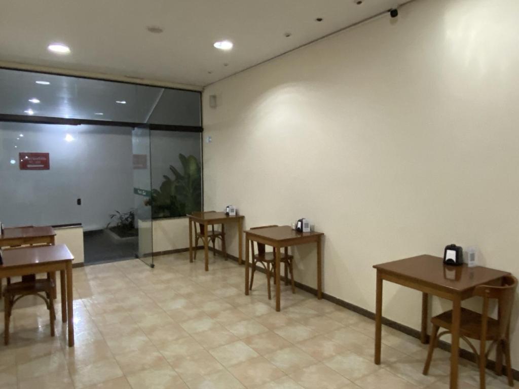 a room with four tables and a white wall at Hotel Valle Sul in Registro