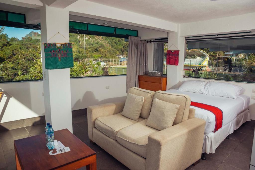 a bedroom with a bed and a couch and a table at El Dragon Hotel in San Marcos La Laguna