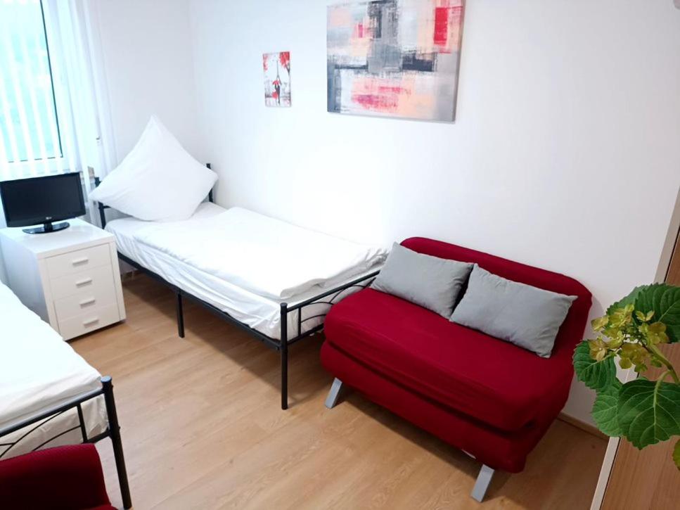 un salon avec une chaise rouge et un lit dans l'établissement Ferienwohnung-Montagewohnung 3, à Bad Driburg