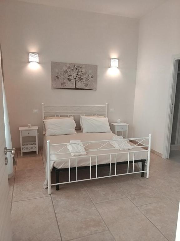 1 cama blanca en una habitación con 2 mesas en Casa Vacanze Livia Maria, en San Cassiano