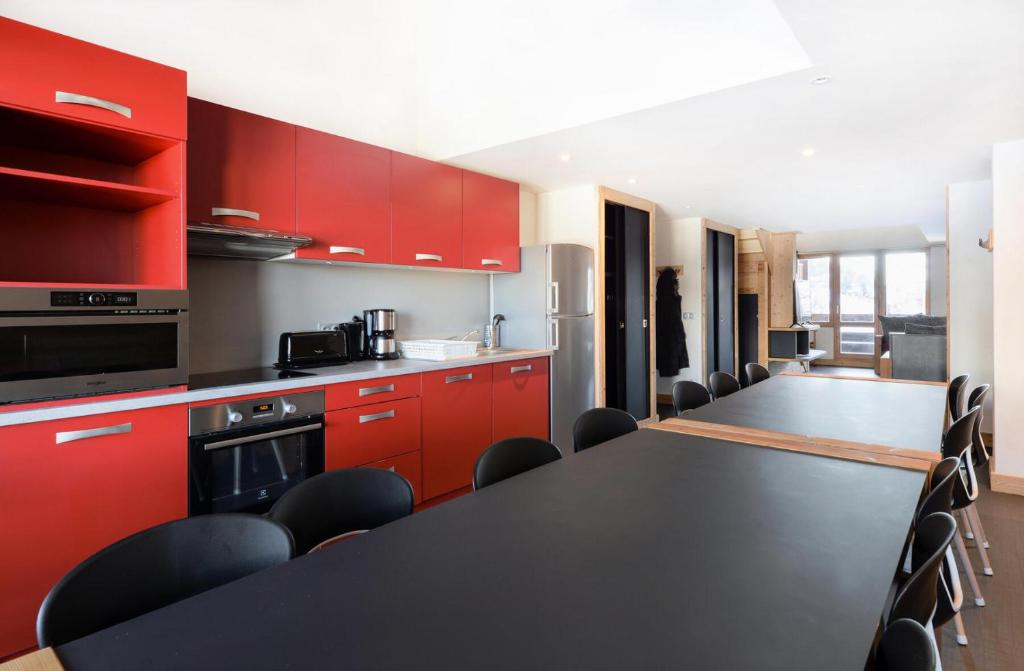 une cuisine avec des armoires rouges et une table et des chaises noires dans l'établissement Résidence Backgammon - LE BACKGAMMON MAE-3417, à Les Coches