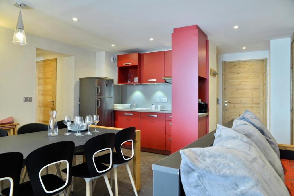 une cuisine avec des armoires rouges et une table et des chaises dans l'établissement Résidence Backgammon - LE BACKGAMMON MAE-3426, à Les Coches