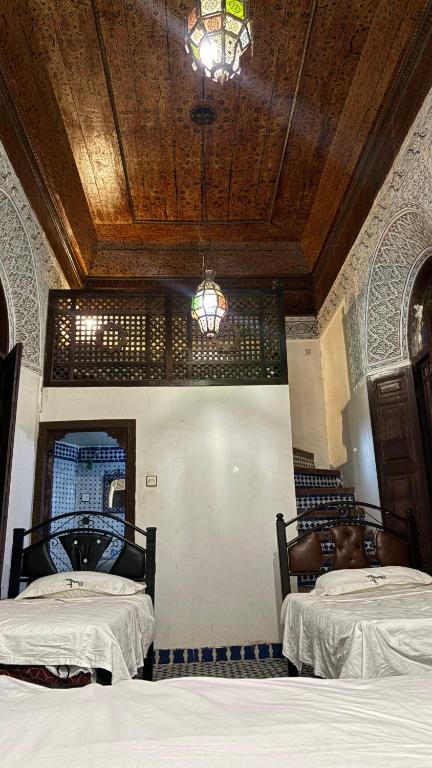 una camera con 2 letti e un soffitto in legno di Dar El Arfaoui a Fes