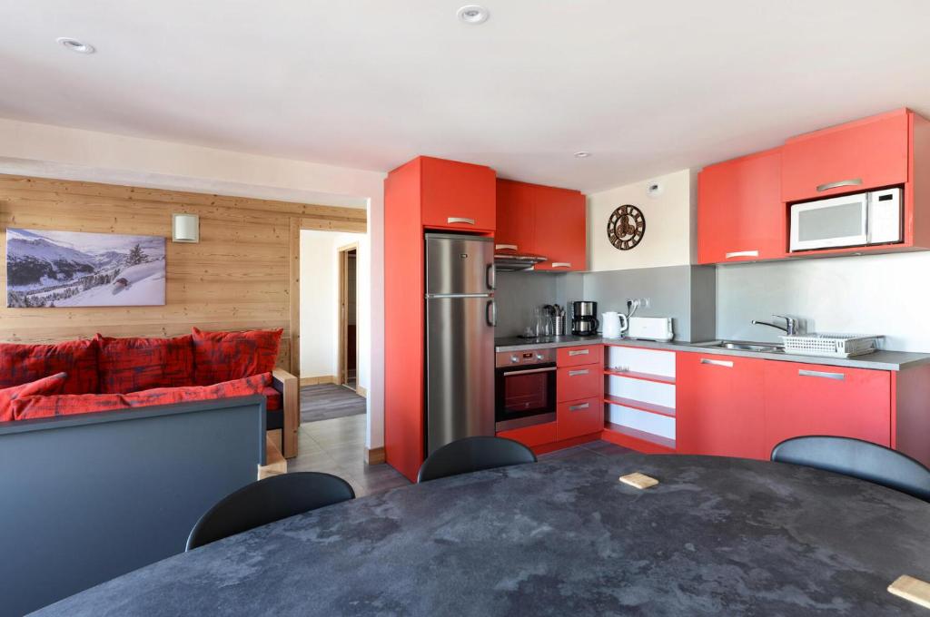une cuisine avec des placards rouges et un canapé rouge dans l'établissement Résidence Backgammon - LE BACKGAMMON MAE-3439, à Les Coches