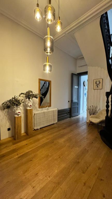 an empty living room with wooden floors and lights at Maison Cosy - Maison de Maitre in Saint-André