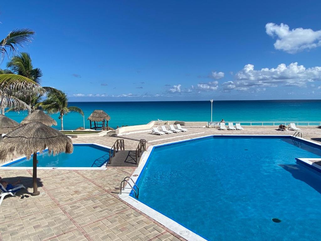 a swimming pool with the ocean in the background at Brisas Shores Beachfront connecting apartments, Cancun Hotel Zone in Cancún