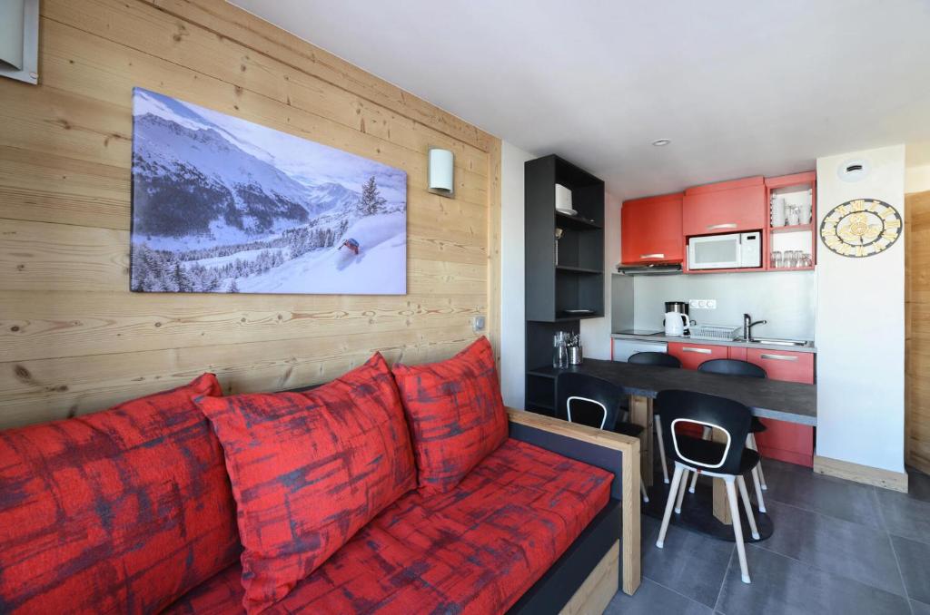 a living room with a red couch and a kitchen at Résidence Backgammon - LE BACKGAMMON MAE-3471 in Les Coches