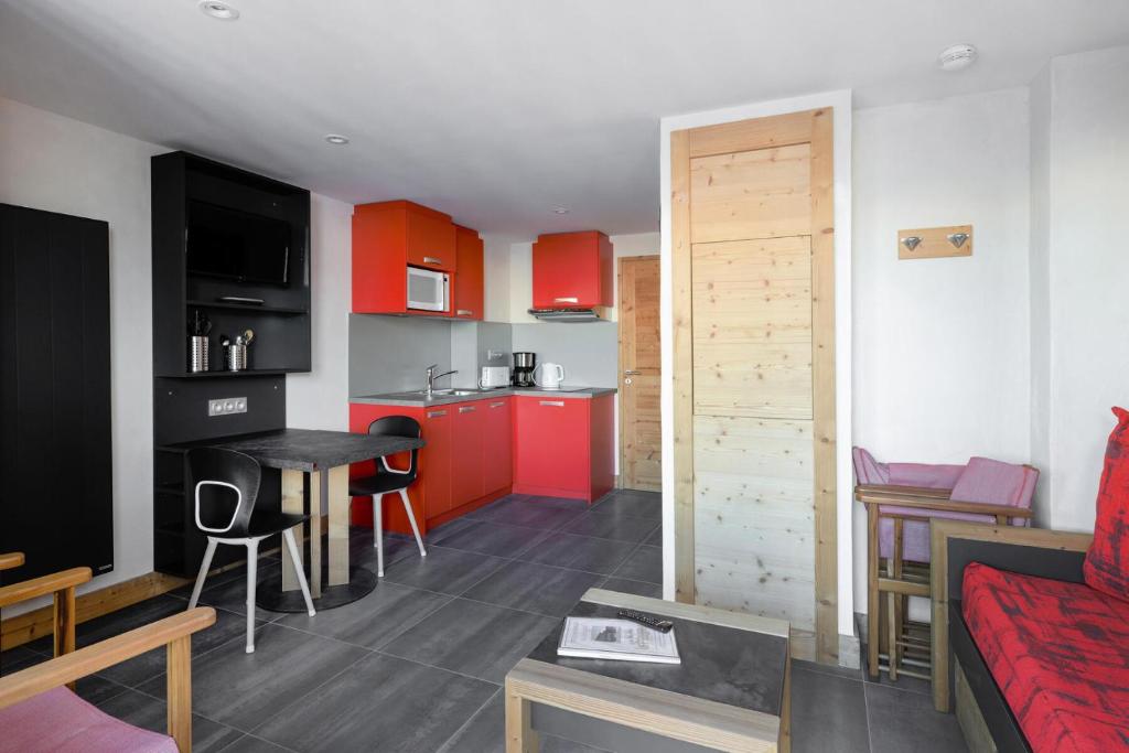 a living room and a kitchen with red cabinets at Résidence Backgammon - LE BACKGAMMON MAE-3559 in Les Coches