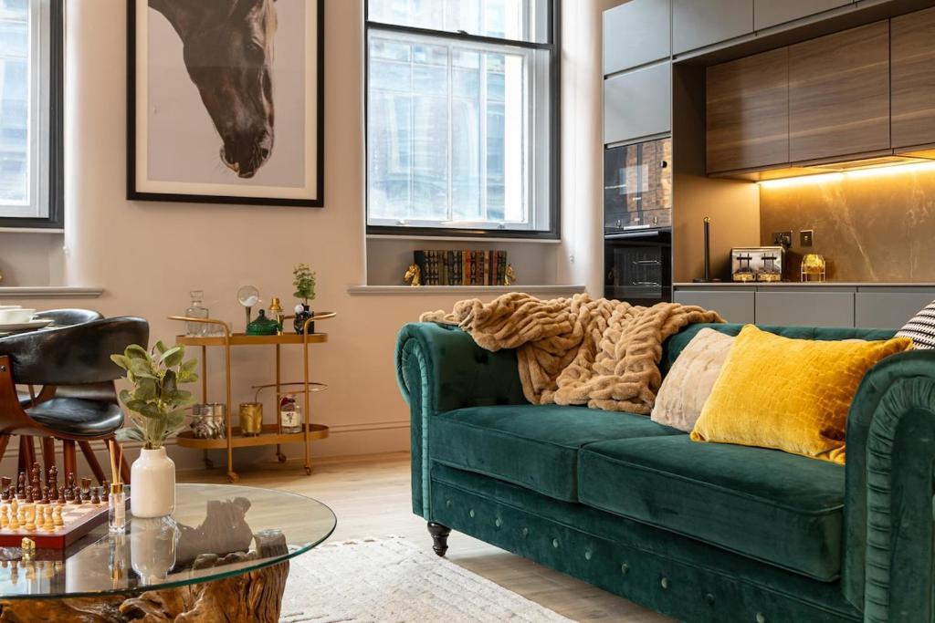un salon avec un canapé vert et une table dans l'établissement Charlotte House Residence by COQOON, à Manchester