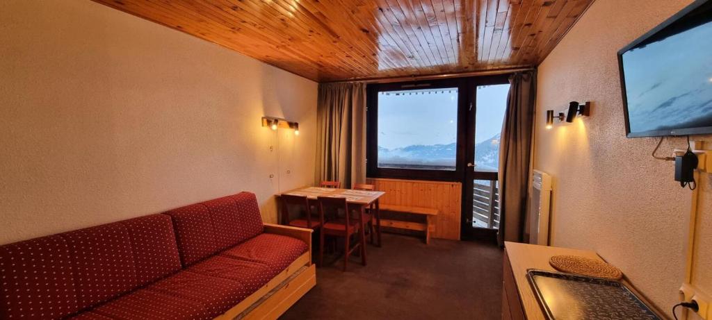 Cette chambre dispose d'un canapé, d'une table et d'une télévision. dans l'établissement Résidence Zodiac - Studio pour 4 Personnes 394, à Aime La Plagne
