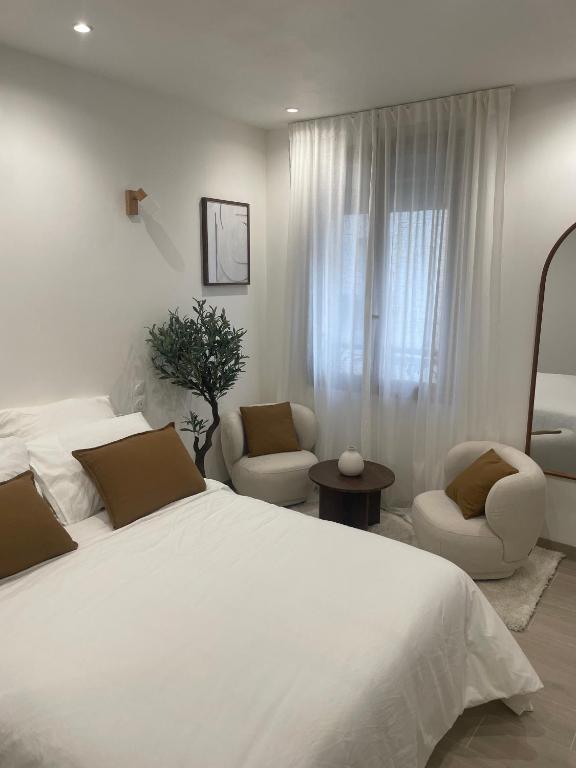 une chambre avec un grand lit blanc et deux chaises dans l'établissement Appartement, à La Plaine-Saint-Denis