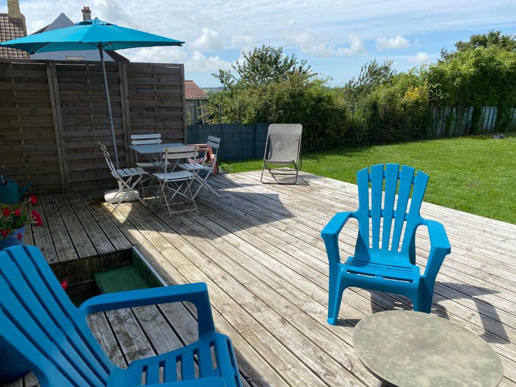 2 chaises bleues, une table et un parasol sur la terrasse dans l'établissement Maison de village avec jardin 15mn des plages, wifi, 2 chambres, jardin, à Hesdin-lʼAbbé