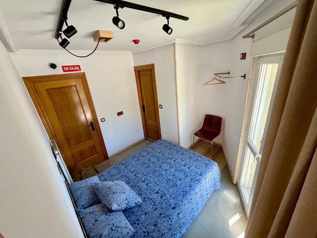 ein kleines Schlafzimmer mit einem blauen Bett und einem Stuhl in der Unterkunft Lotila Flats Rio Caudal in Figaredo