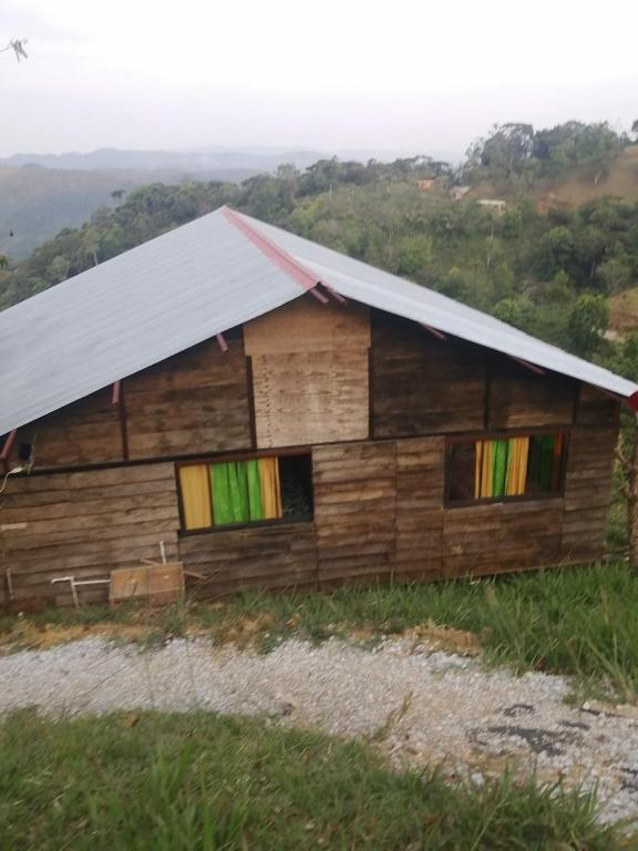 a wooden house with a tin roof on a hill at Cabaña la fundadora in San Luis