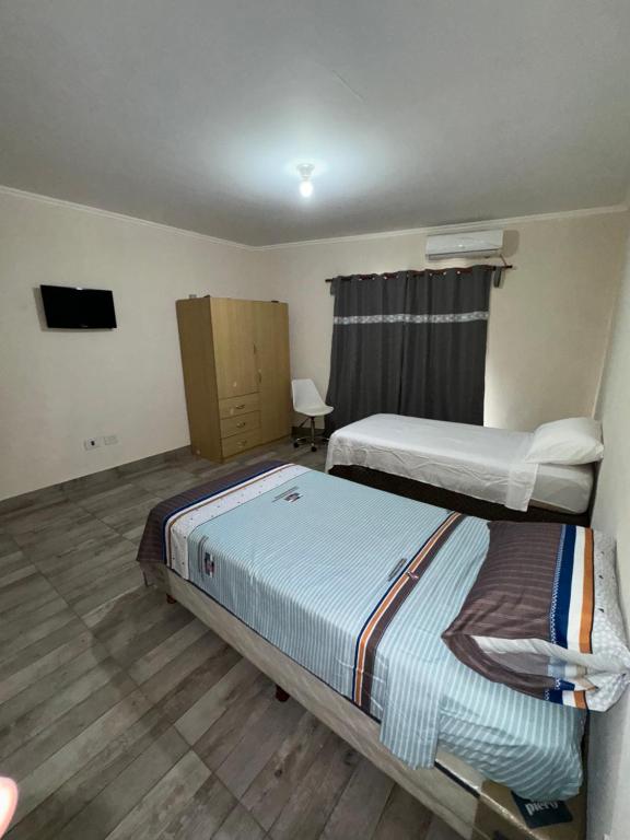 Una habitación de hotel con dos camas y un televisor. en Residencia Las Américas, en Garupá