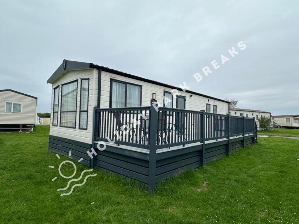 a small house with a dog sitting on the front porch at Seagull Cove - 3bed at Seal Bay Resort in Selsey in Selsey