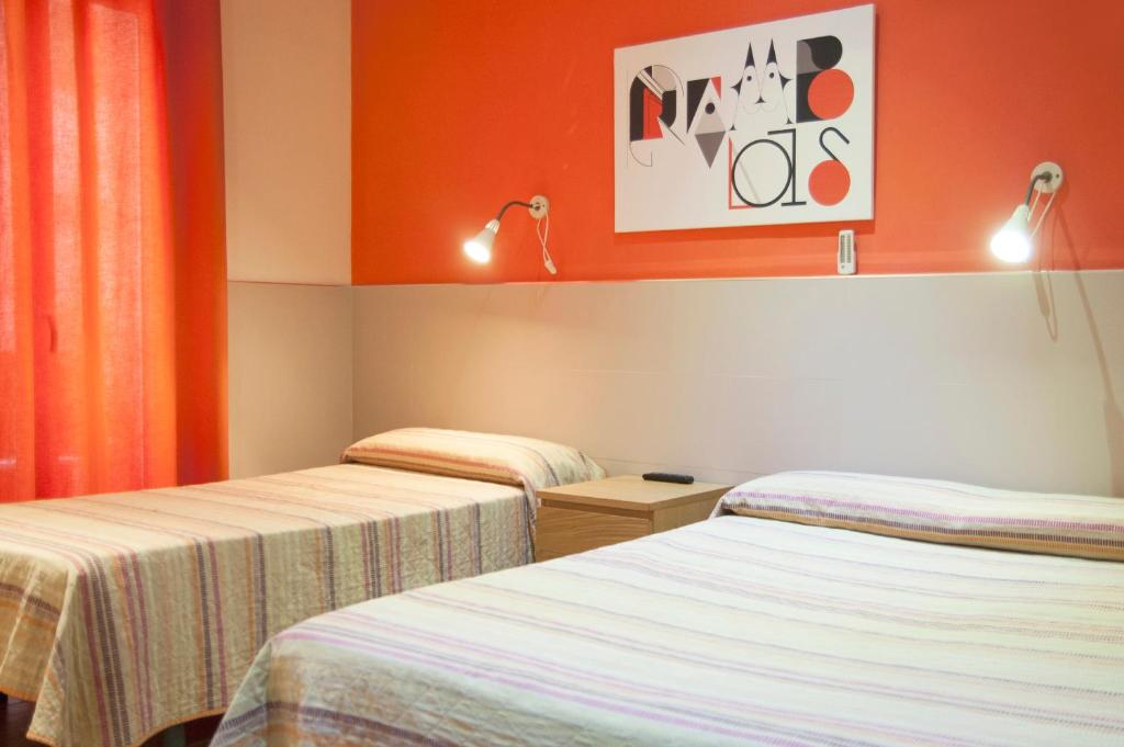 バルセロナにあるビー ランブラス ゲストハウスのオレンジ色の壁の客室内のベッド2台